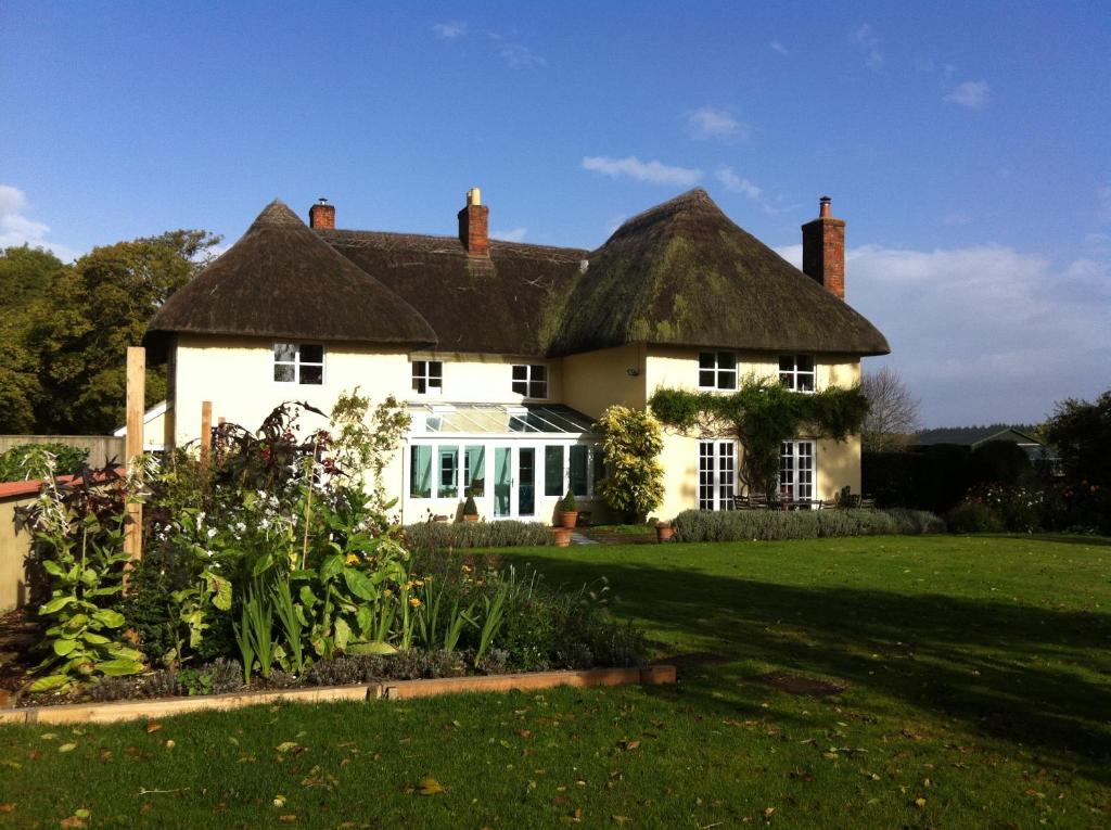 a large white house with a thatched roof at Gunville House B&B in Grateley