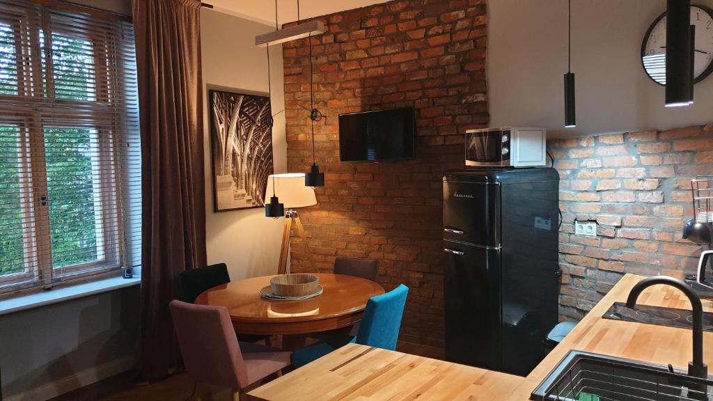 a kitchen with a table and a black refrigerator at Apartament Wysoka Brama 1/4 in Gryfice