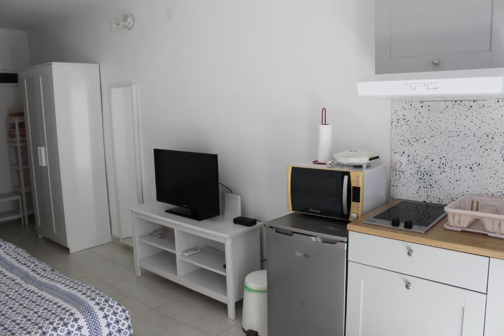 a kitchen with white cabinets and a tv on a counter at Apartments Estelle in Pula
