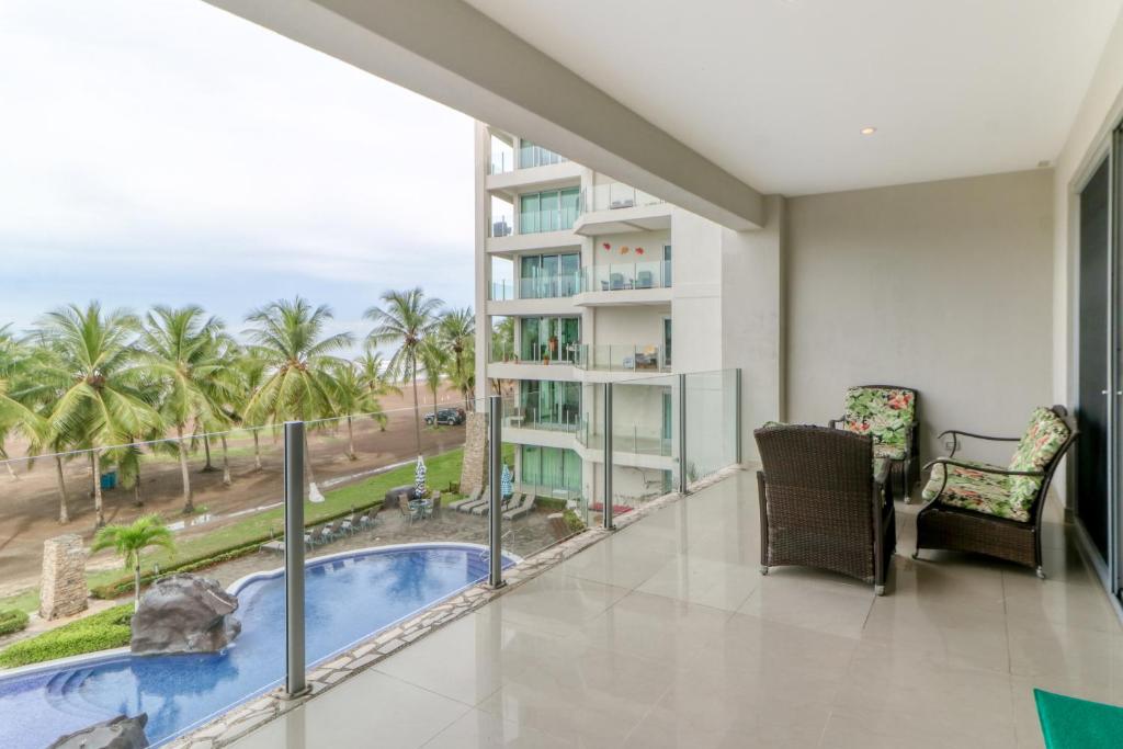 balcón con vistas a la piscina y a las palmeras en Diamante del Sol 302s, en Jacó