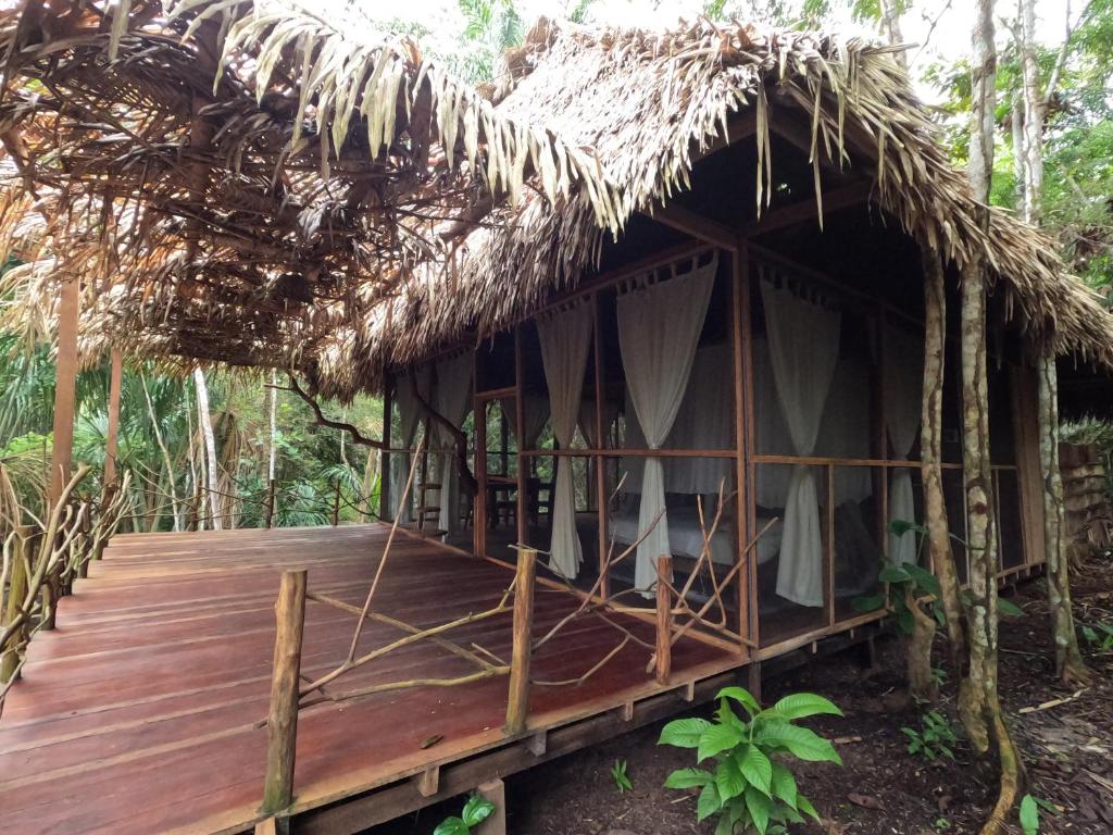 Une cabane au toit de chaume avec une terrasse dans les bois dans l'établissement Enchanting Jungle Villa — UMARI, à Iquitos