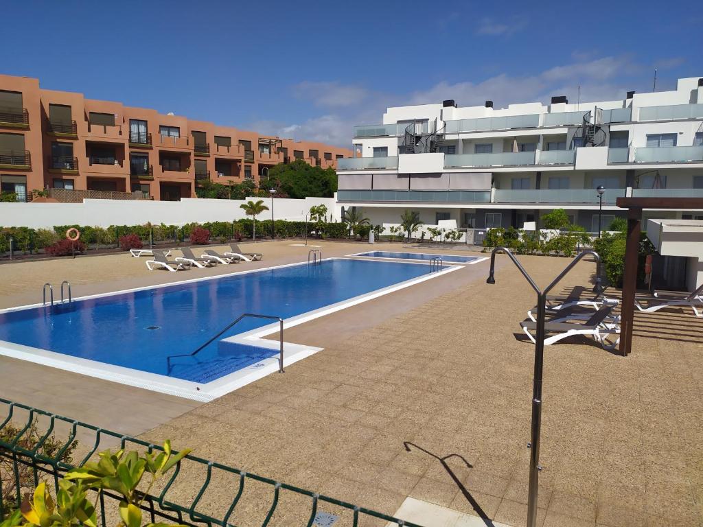 une grande piscine en face d'un bâtiment dans l'établissement Bonito piso con piscina, playa la Tejita, à La Tejita