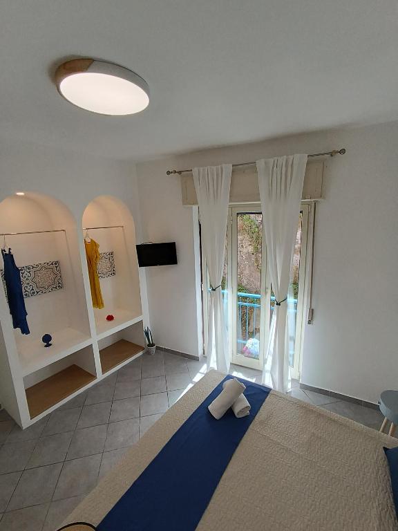 sypialnia z niebieskim łóżkiem i oknem w obiekcie Maison Clemi w Sorrento