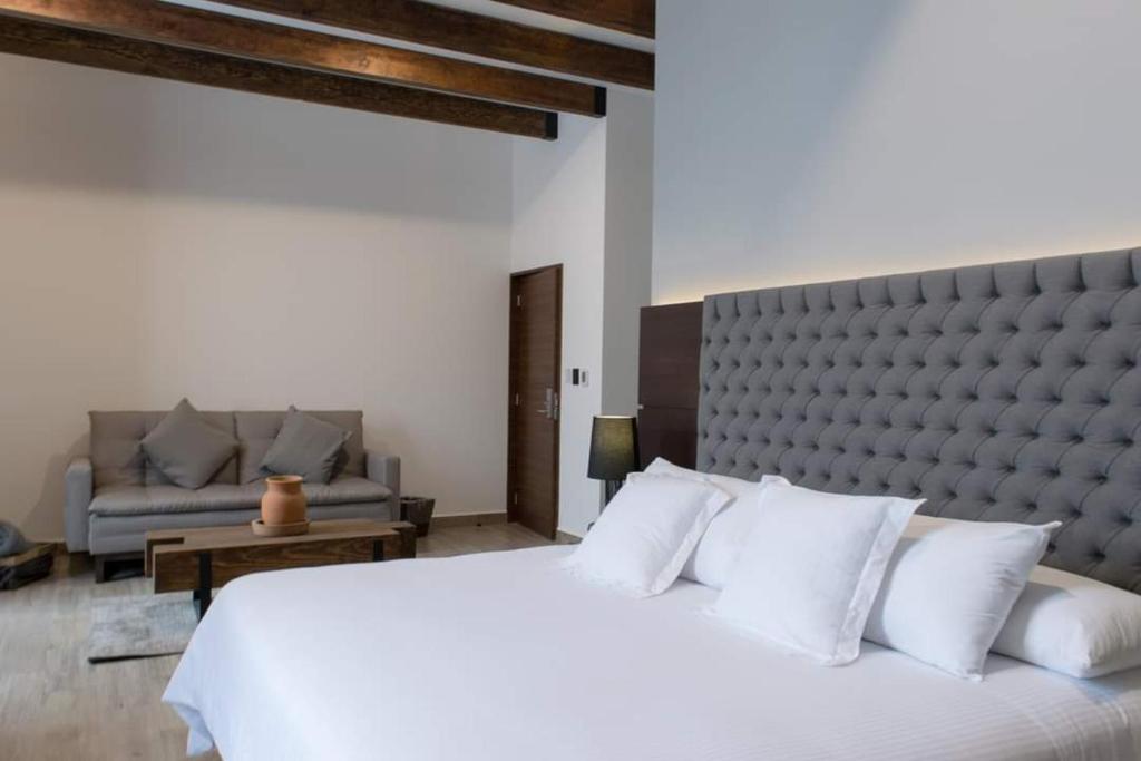 a bedroom with a large white bed and a couch at Hotel Diana in Puebla