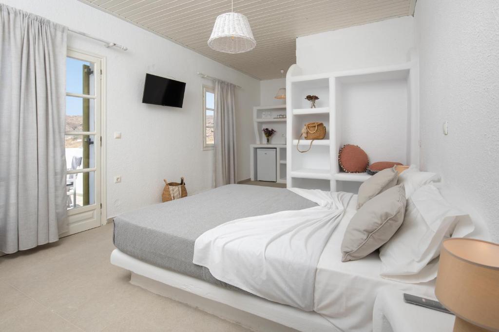 a white bedroom with a bed and a tv at Vavoulas Village in Mikri Vigla