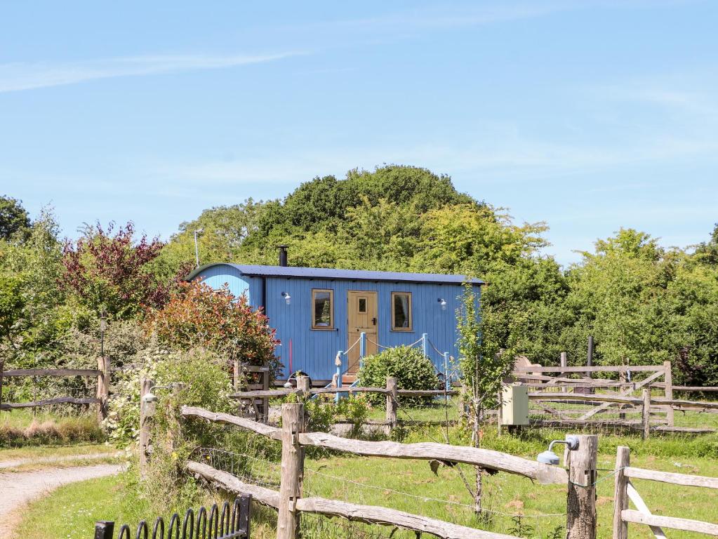 a blue trailer in a field next to a fence at The Clydes in Tremeirchion