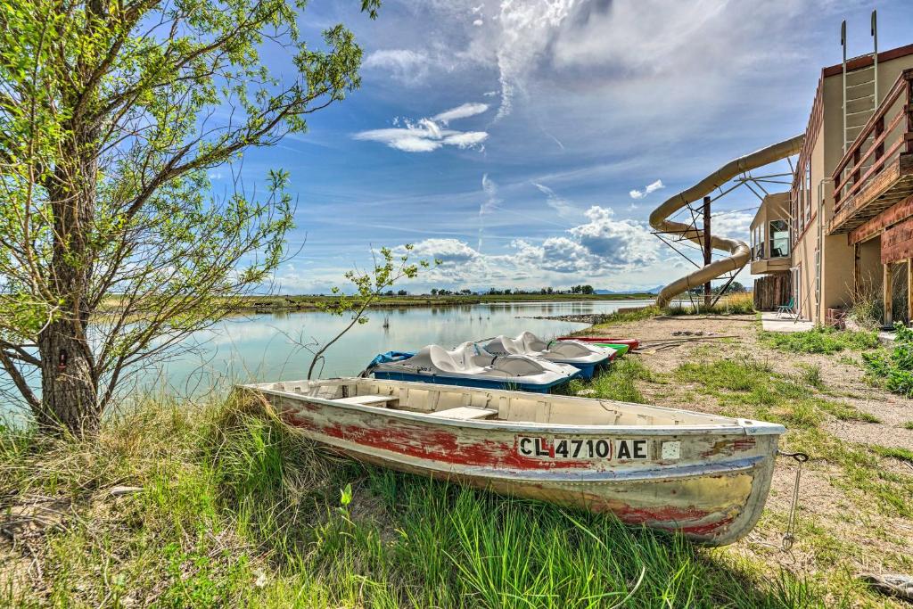 a boat sitting on the side of a body of water at Lakefront Country Home with Waterslide and Trampoline! in Wheatland
