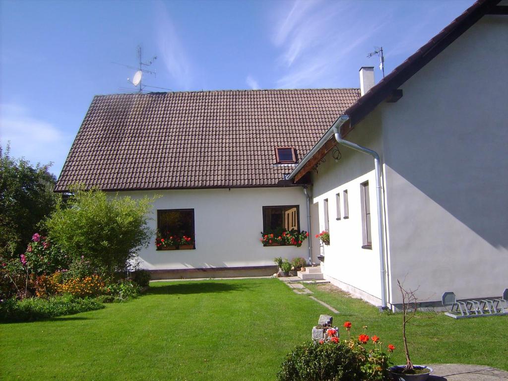a white house with a green yard with flowers at Penzion ALEXSPORT in Třeboň