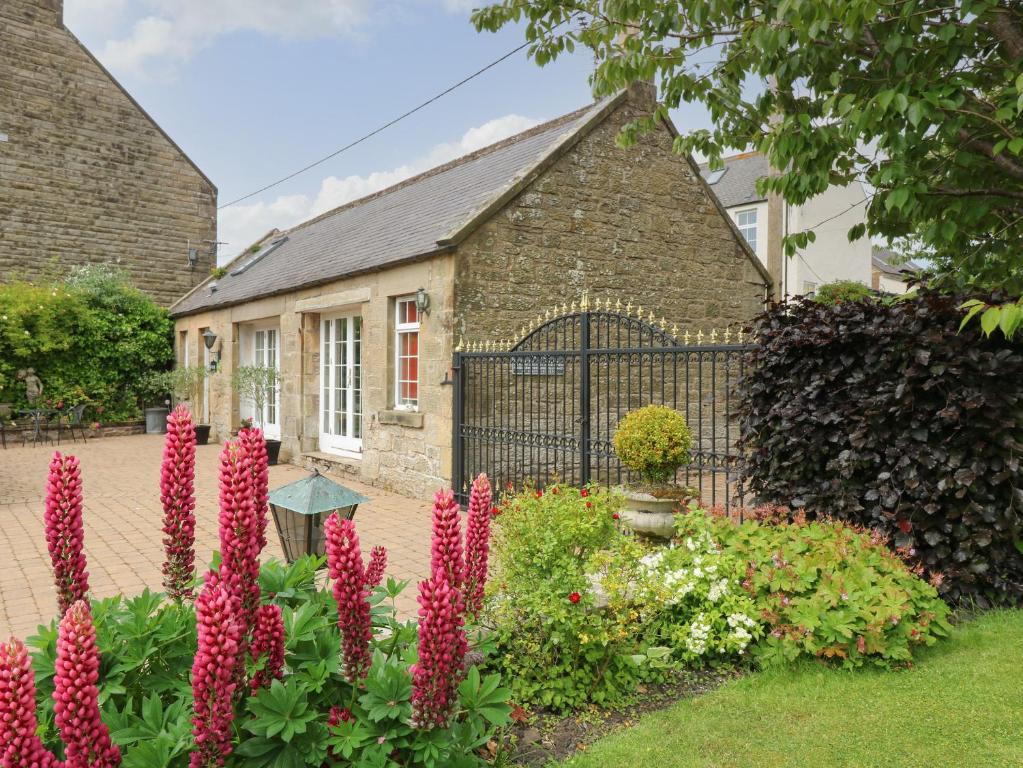 a garden with pink flowers in front of a building at The Coach House in Duns