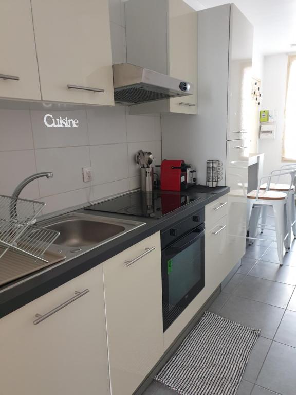 une cuisine blanche avec un évier et une cuisinière dans l'établissement Une heureuse coïncidence, à Montpellier