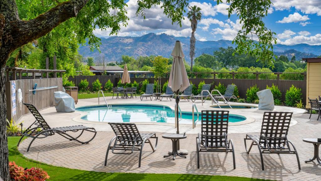 eine Terrasse mit Stühlen, einem Pool und einem Sonnenschirm in der Unterkunft The Inn on Pine in Calistoga