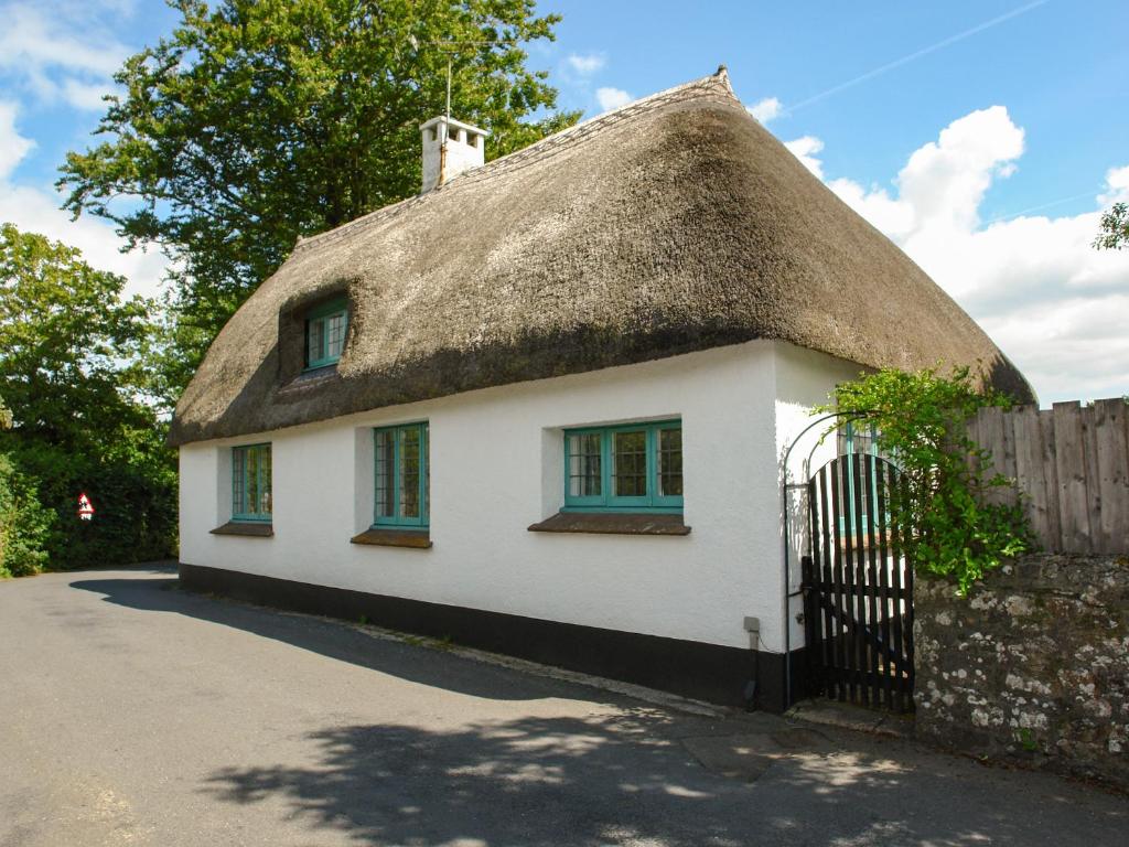 a small white house with a thatched roof at The Old Forge in Newton Abbot