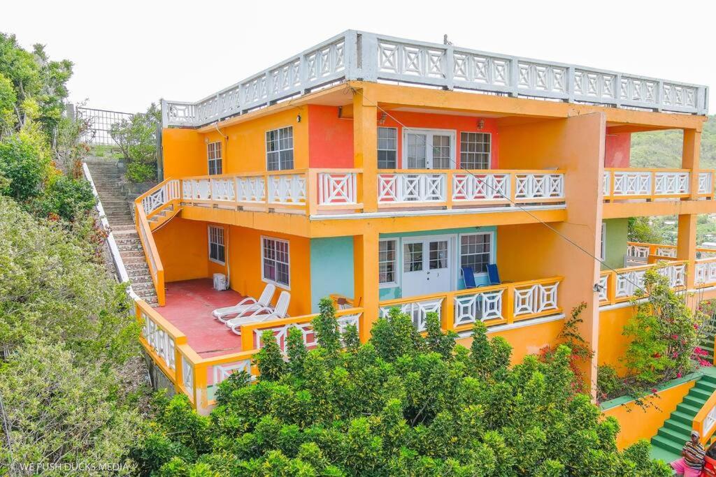 ein orangefarbenes Haus mit weißen Balkonen und Bäumen in der Unterkunft Belle View-Tulip in Laborie