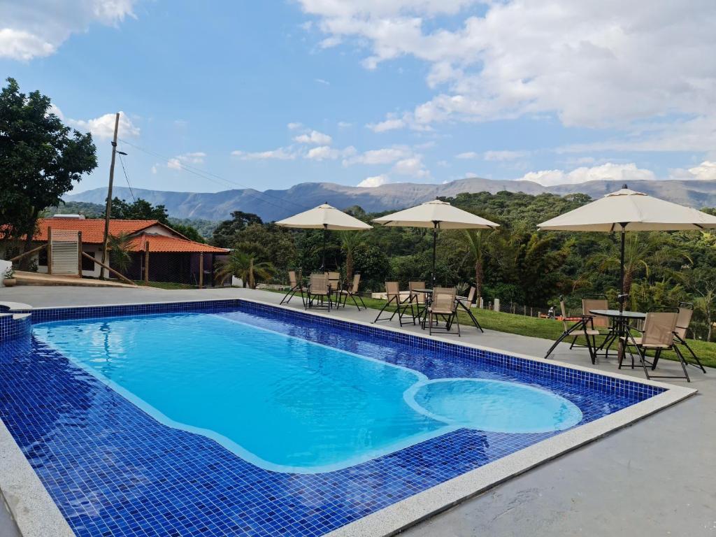 - une piscine avec des chaises, des tables et des parasols dans l'établissement Pousada Descobrindo a Vida, à Brumadinho