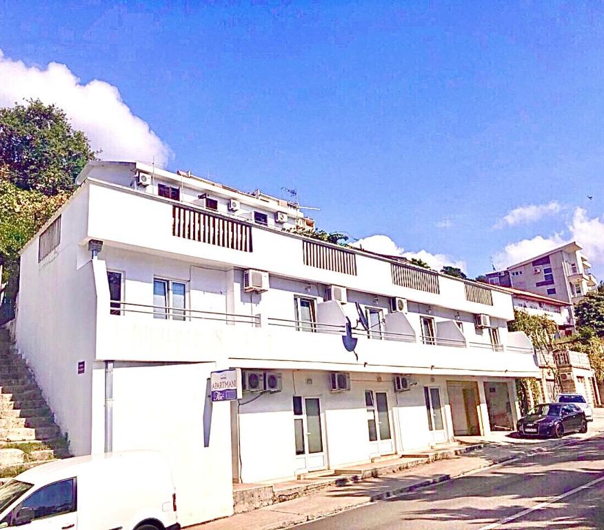 a white building with a car parked in front of it at Apartmani Ilić in Herceg-Novi