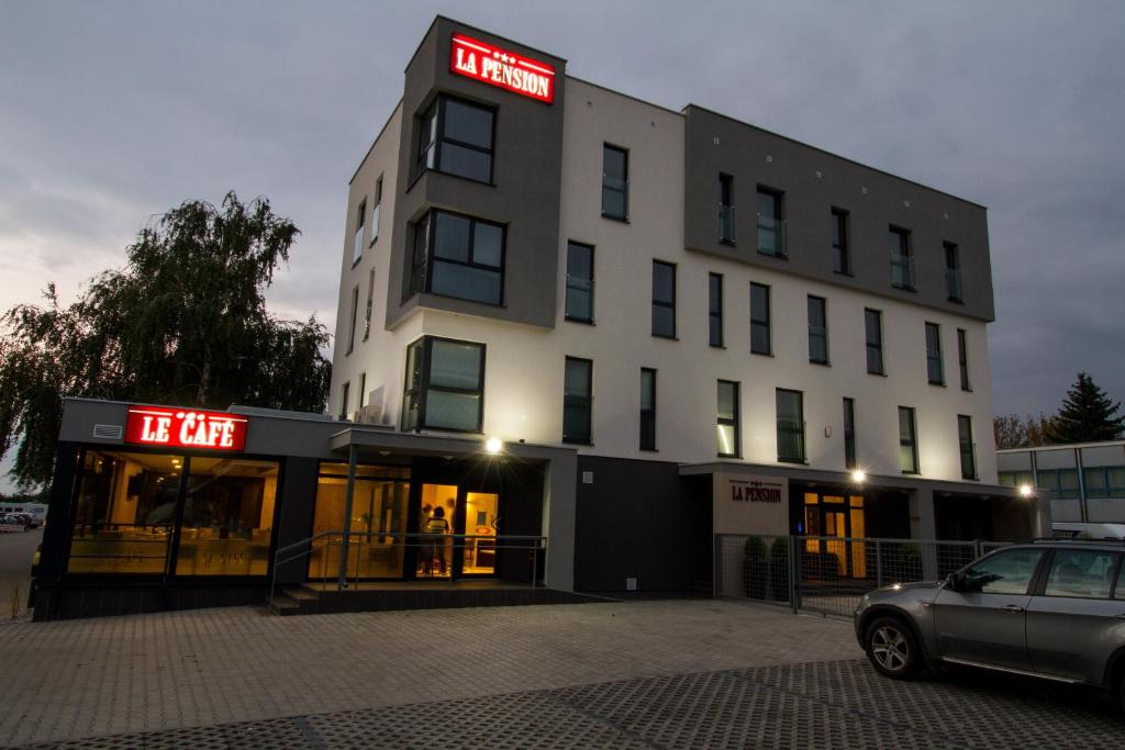 un edificio blanco con un letrero de neón rojo. en La Pension en Trnava