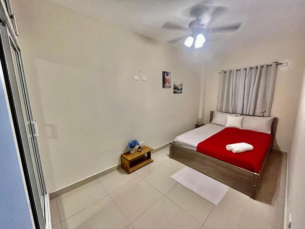 um quarto com uma cama vermelha e uma ventoinha de tecto em Oasis de Paz 1.2 em Jarabacoa