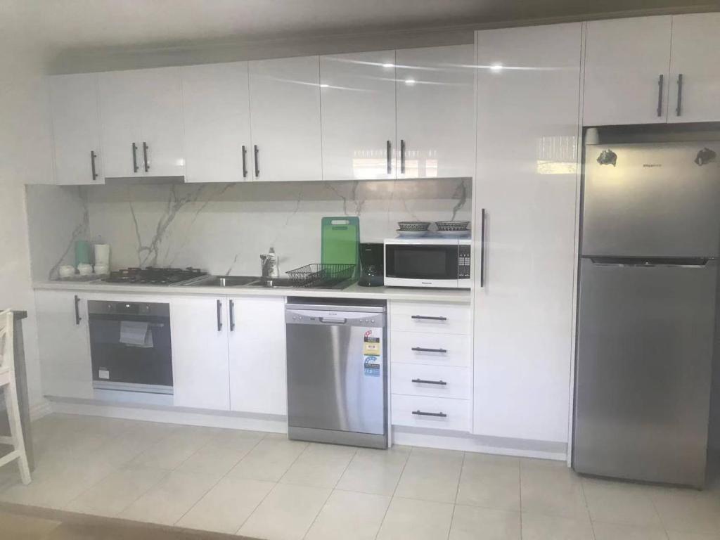 una cocina con armarios blancos y electrodomésticos de acero inoxidable en Oakleigh Private unit en Oakleigh