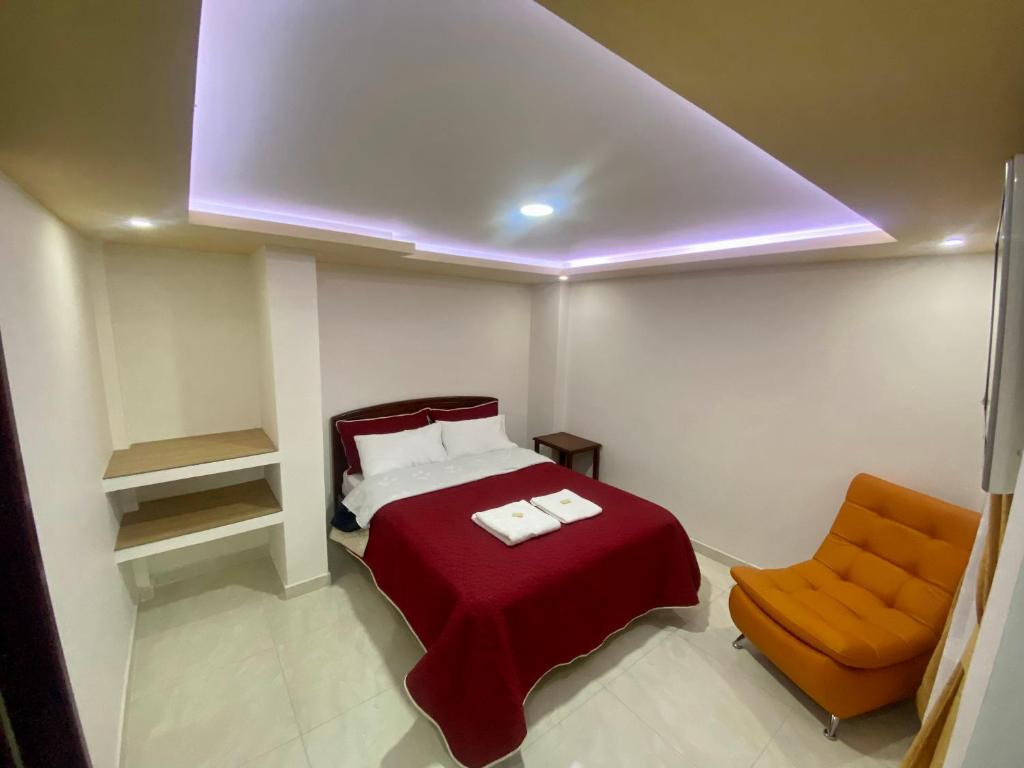 a bedroom with a red bed and a chair at Hotel Dubai Suite in Pasto