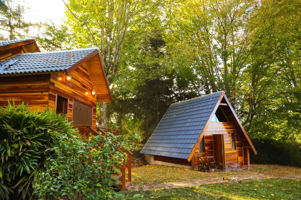 a wooden cabin with a solar roof on a forest at Villa Iturri in Campos do Jordão