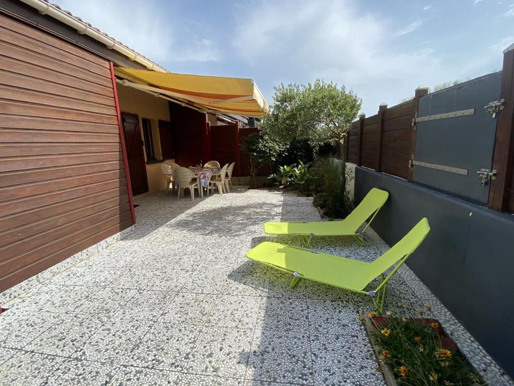 un patio con 2 sillas verdes y una casa en Villa Capbreton, 2 pièces, 4 personnes - FR-1-413-180, en Capbreton