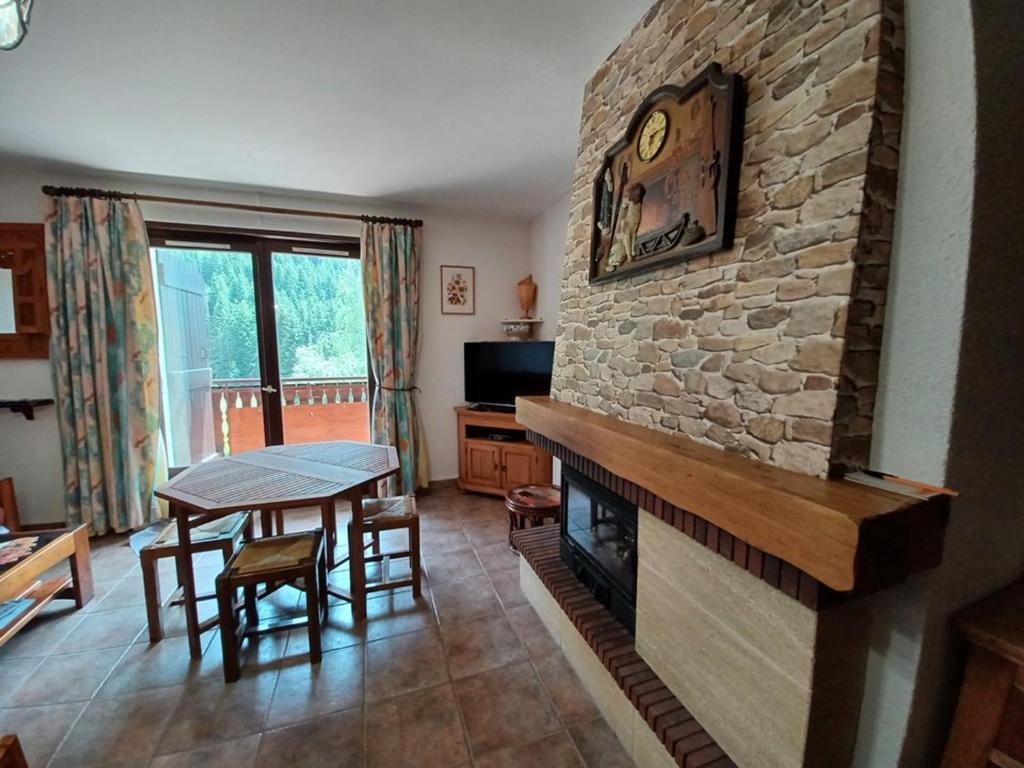 a living room with a stone fireplace and a table at Charmant 2 pièces avec balcon et parking au Col du Corbier - FR-1-573-107 in Le Biot