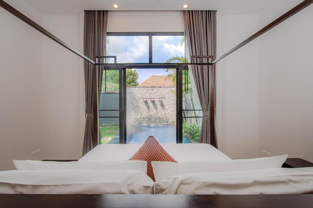1 dormitorio con 2 camas y ventana grande en One Bedroom Onyx Villa Nai Harn, en Nai Harn Beach