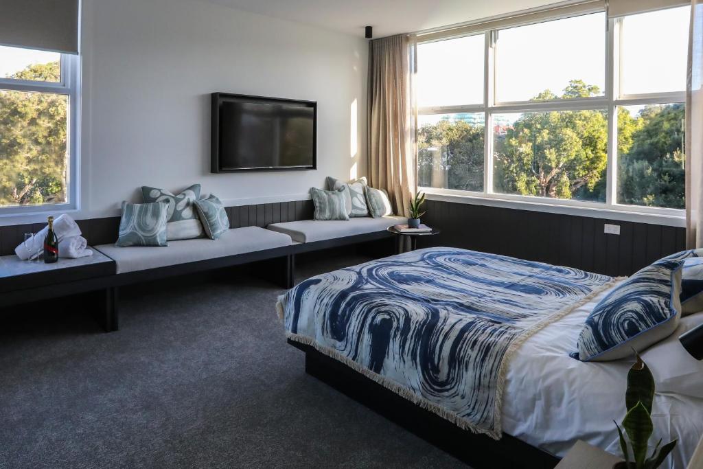 a bedroom with a bed and a tv and windows at Beach Road Hotel in Sydney