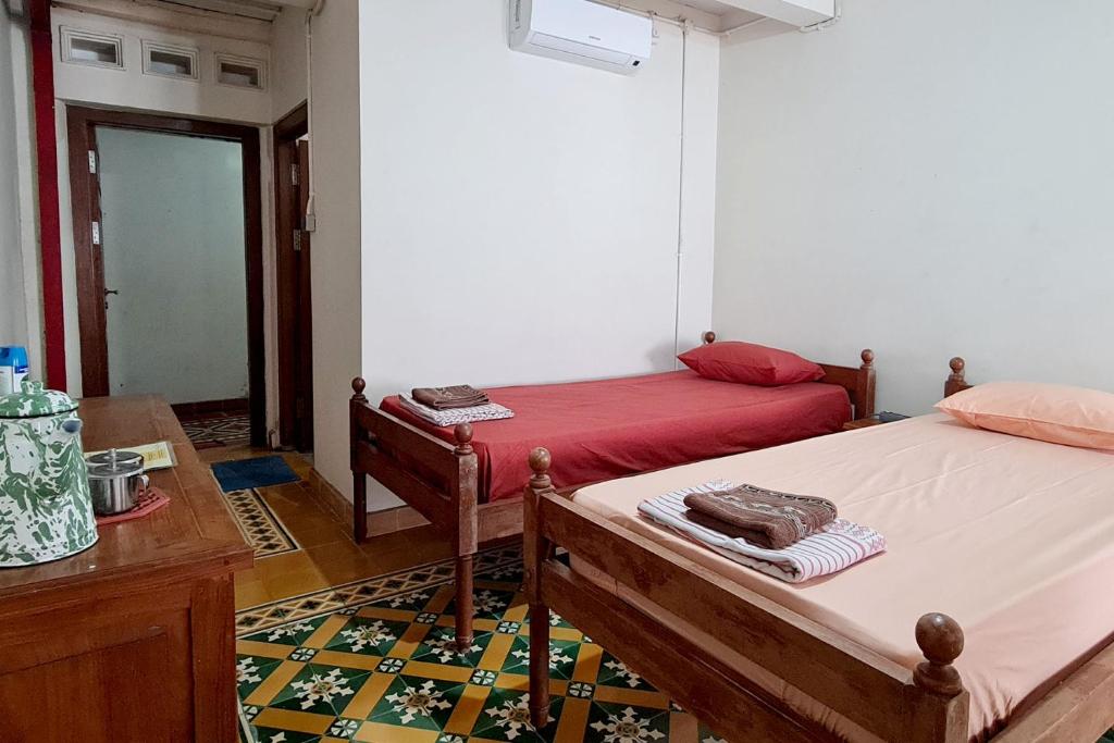a room with two beds and a table in a room at Omah Pitoe Yogya Homestay in Yogyakarta