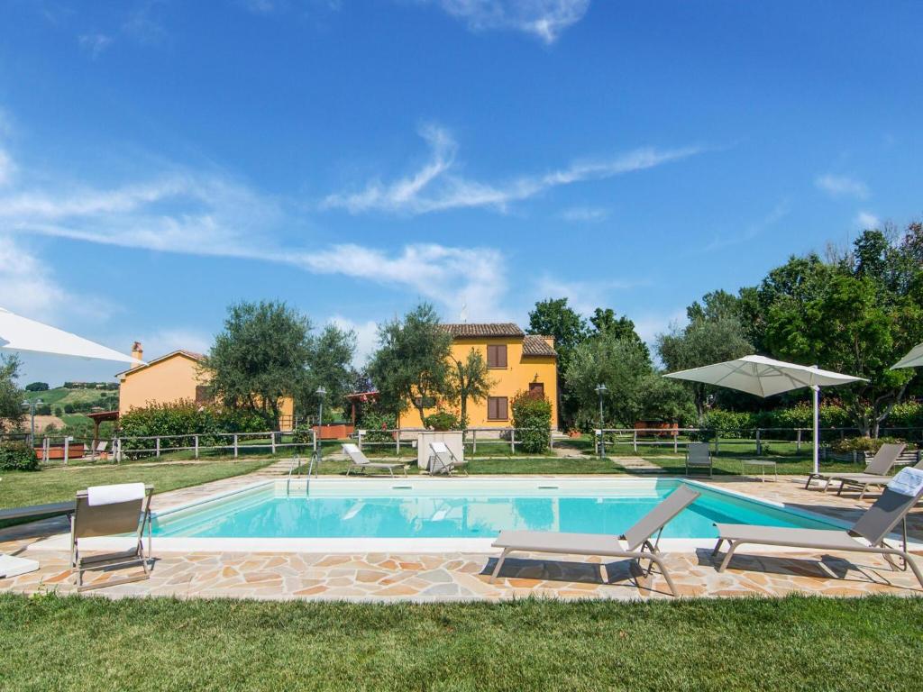 a pool with chairs and a house in the background at Holiday Home in Marche region with Private Swimming Pool in Ostra Vetere