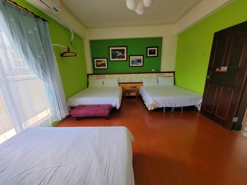 a room with two beds and green walls at 草莓牛奶台東民宿可洽包棟 in Taitung City