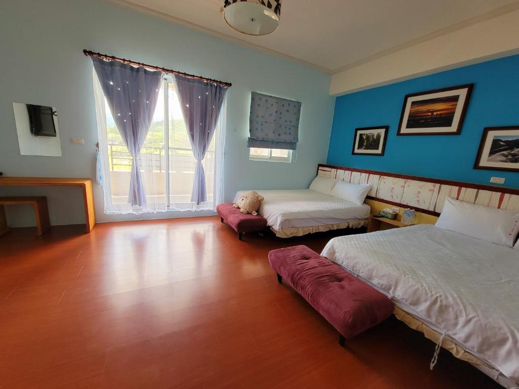 a bedroom with two beds and a large window at 草莓牛奶台東民宿可洽包棟 in Taitung City