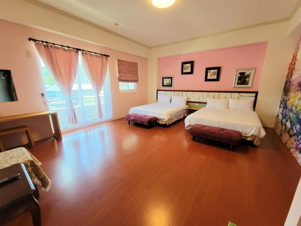 a bedroom with two beds and a wooden floor at 草莓牛奶台東民宿可洽包棟 in Taitung City