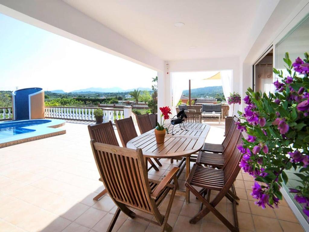 een patio met een houten tafel, stoelen en bloemen bij Traditional holiday home in Teulada with private pool in Teulada