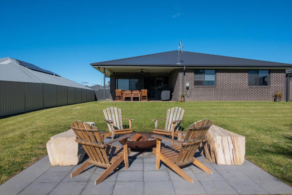 a patio with three chairs and a table with a fire pit at 'Campanile House' The Ultimate Mudgee Adventure in Mudgee