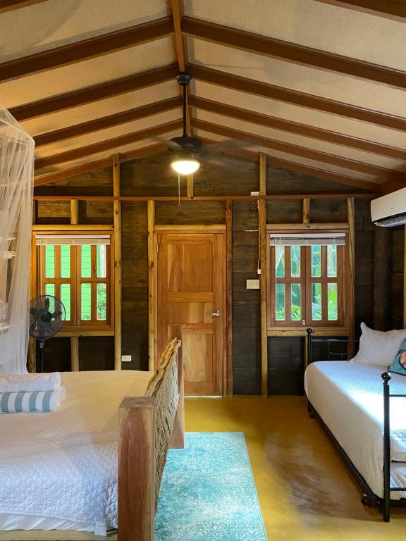 two beds in a room with wooden walls and windows at Bak A Yaad in Negril