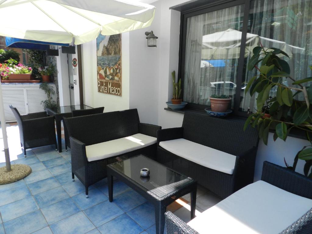 a patio with chairs and tables and an umbrella at Hotel Punta Mesco in Monterosso al Mare