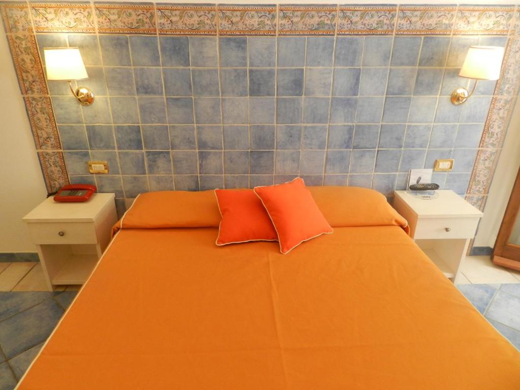 a bedroom with an orange bed with two orange pillows at Hotel Punta Mesco in Monterosso al Mare