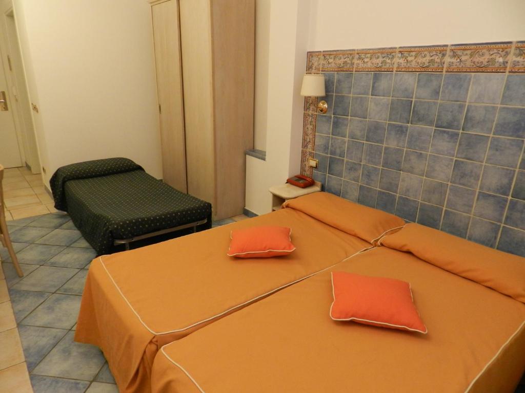 a bedroom with a bed with orange sheets and a chair at Hotel Punta Mesco in Monterosso al Mare