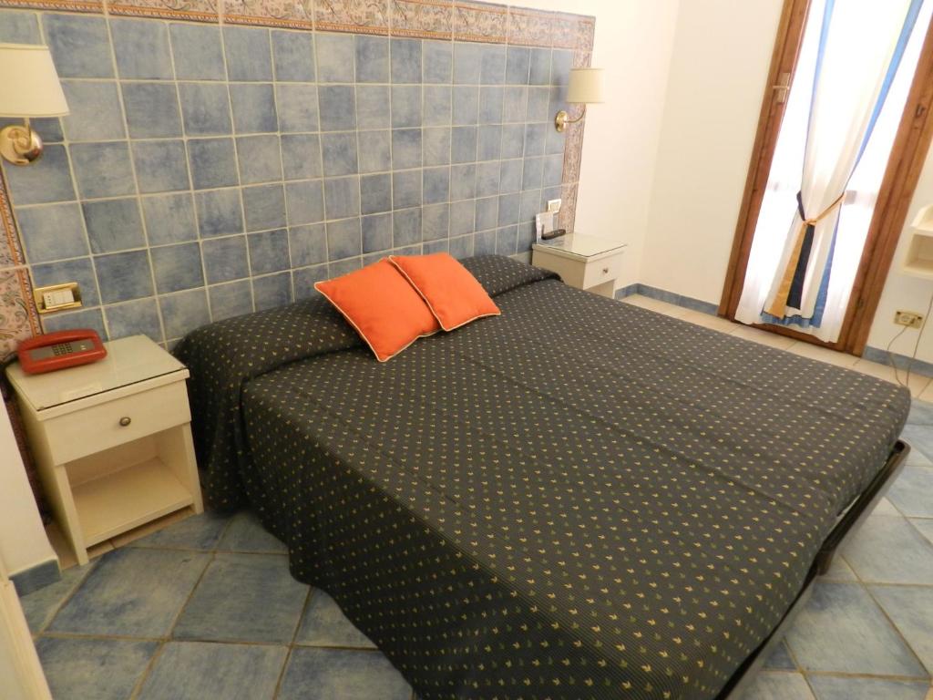 a small bedroom with a black bed with orange pillows at Hotel Punta Mesco in Monterosso al Mare