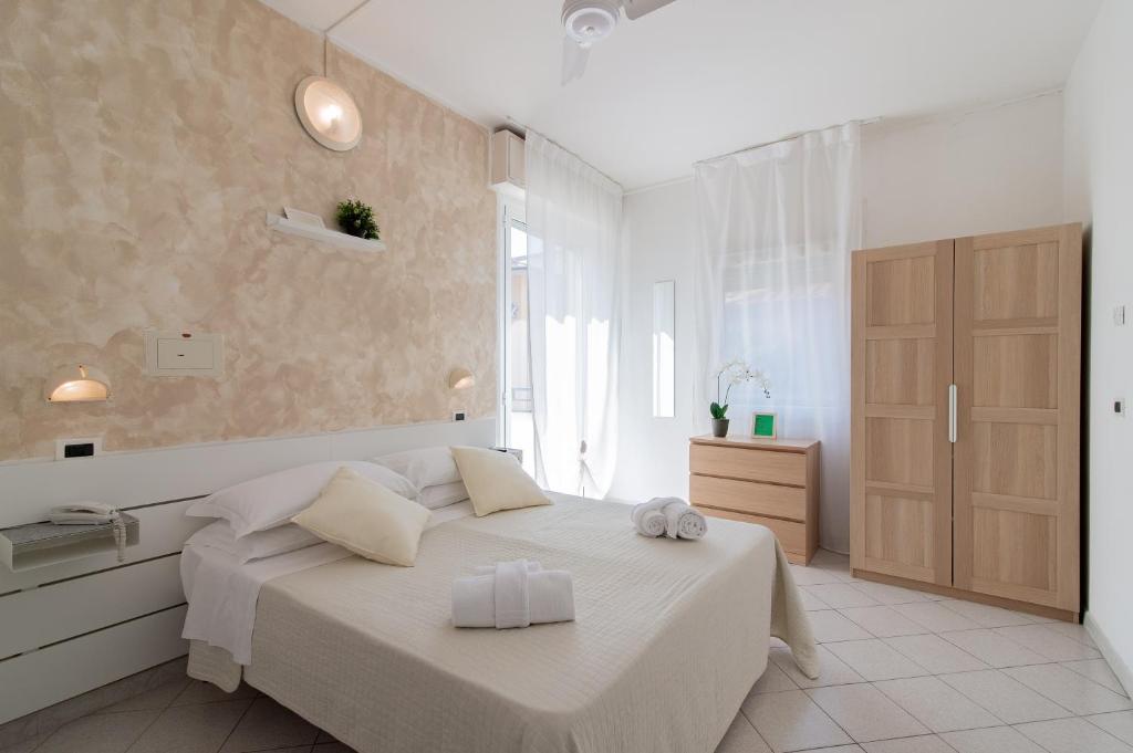 een witte slaapkamer met een bed en een raam bij HOTEL JOHN in Rimini