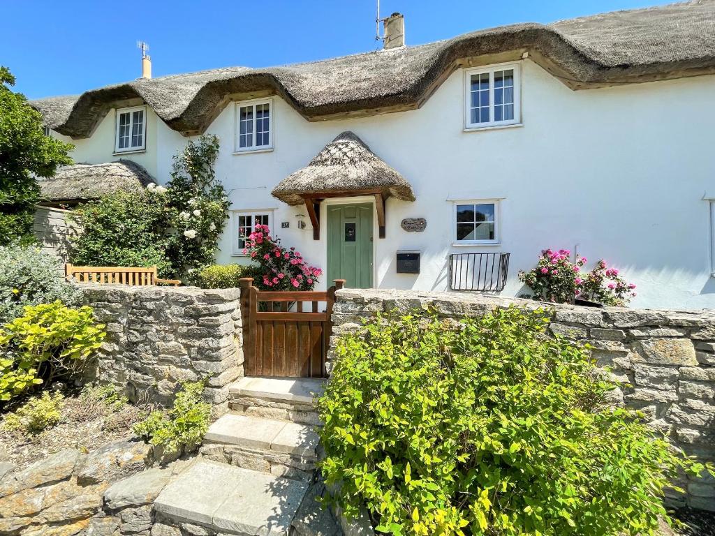 ein weißes Haus mit einem Strohdach in der Unterkunft Cajun Cottage in Wareham