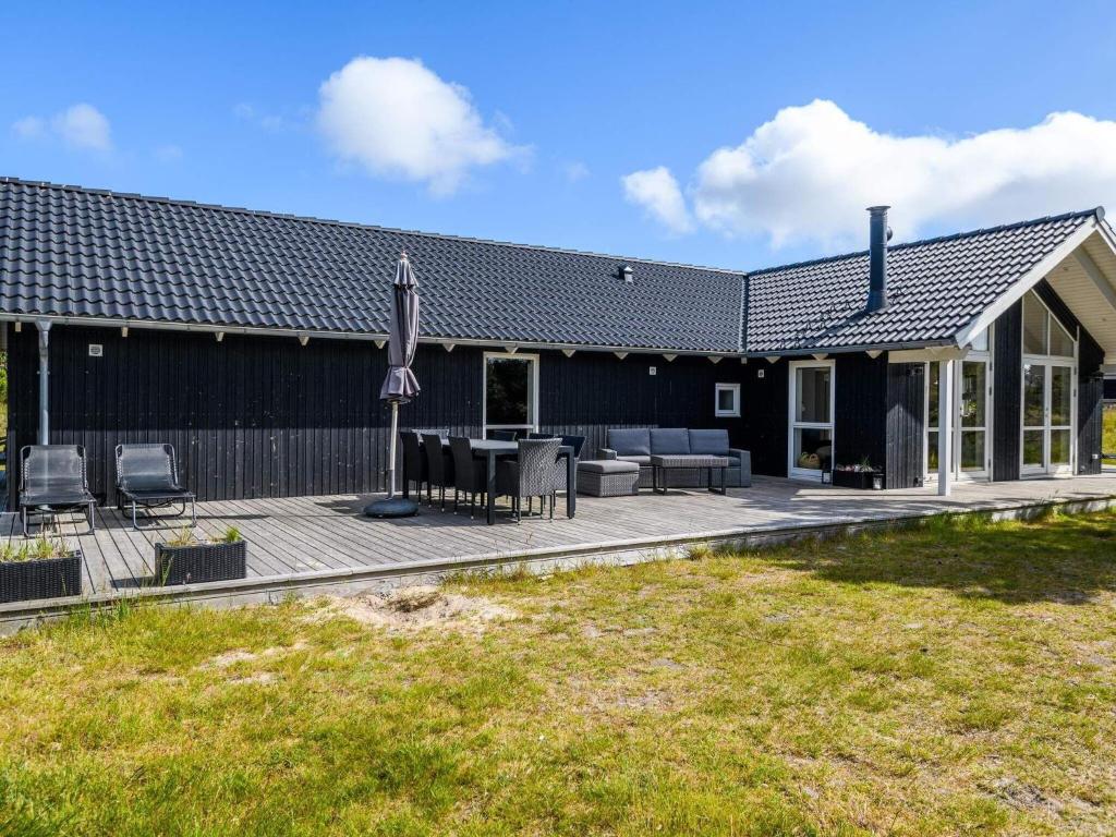ein Haus mit einer Terrasse mit einem Tisch und Stühlen in der Unterkunft Holiday home Fanø XLIII in Fanø