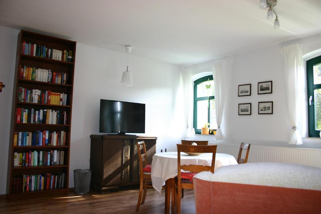 ein Wohnzimmer mit einem Tisch, einem TV und Büchern in der Unterkunft Apartment Jakobsweg GbR in Pettstädt