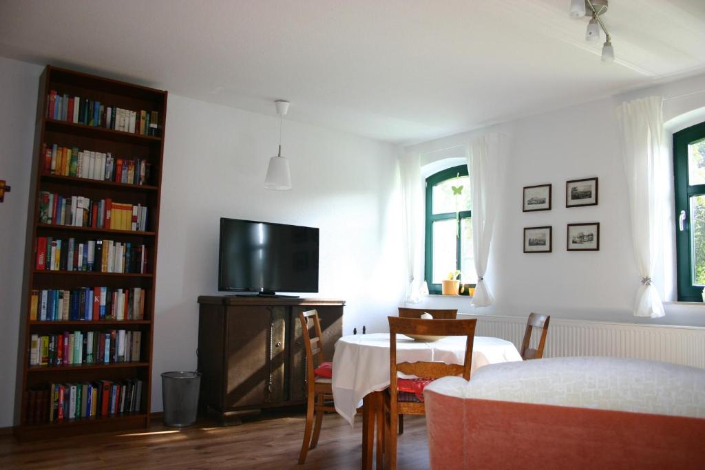 a living room with a table and a tv and books at Apartment Jakobsweg GbR in Pettstädt