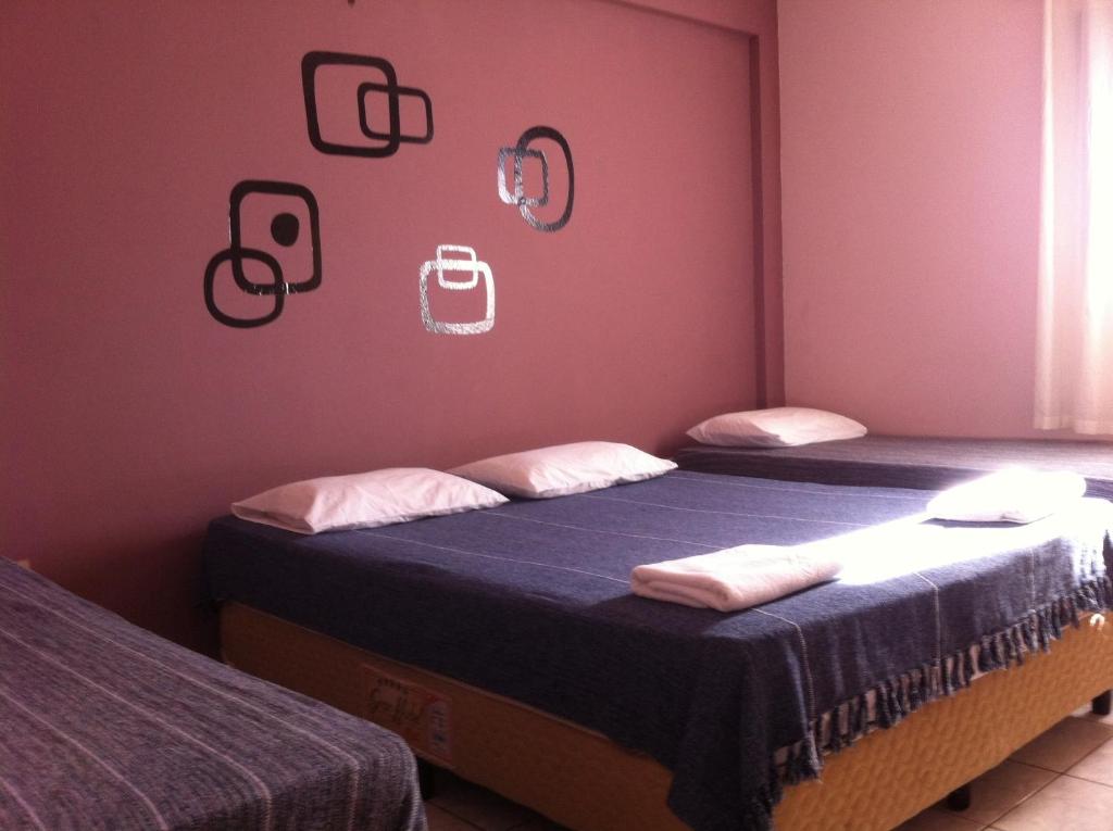 two twin beds in a room with pink walls at 50 Hotel in Extrema