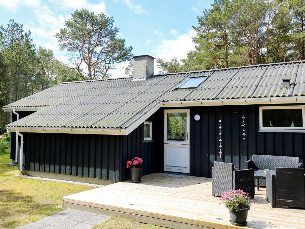 cobertizo negro con puerta blanca y patio en Holiday Home Jægerparken, en Odde