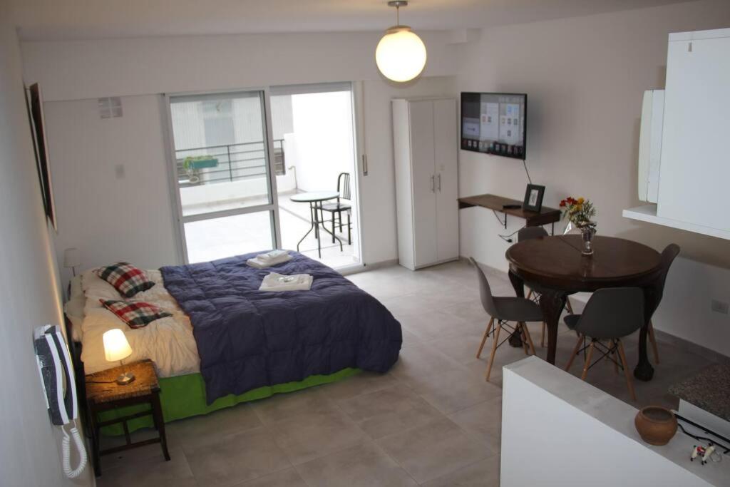 Un dormitorio con una cama y una mesa y una cocina. en Apart con Patio Exclusivo - Rosario Centro - Excelente - Cochera Opcional, en Rosario