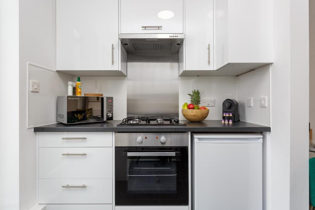 a white kitchen with a stove and a microwave at Milton Heights - Modern 2 bedroom apartment with terrace in Portsmouth in Portsmouth