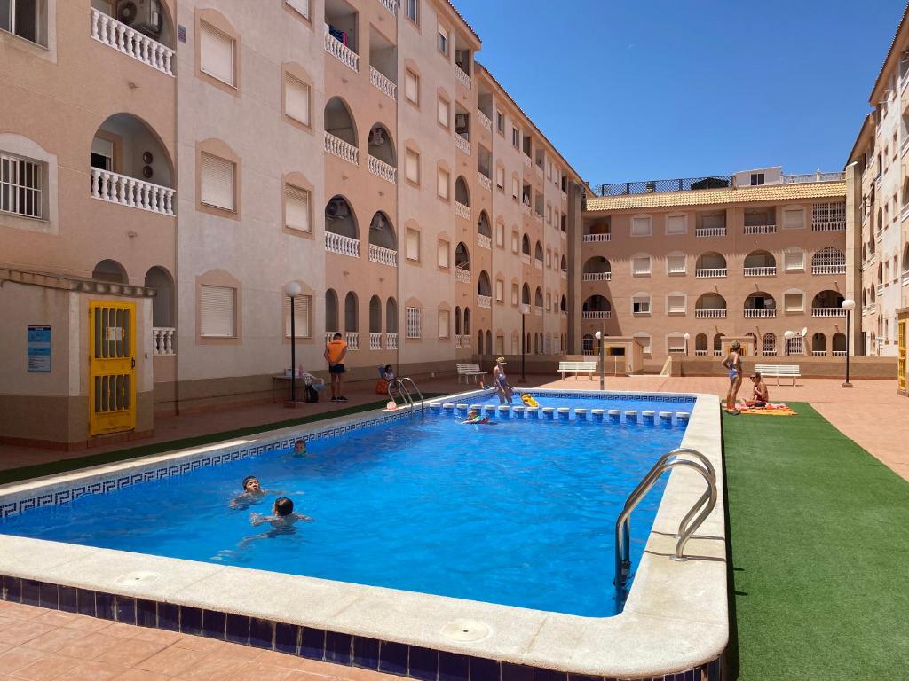 un groupe de personnes dans une piscine située dans un bâtiment dans l'établissement Amazing 2-bedrooms apartment with pool Torrevieja center, à Torrevieja